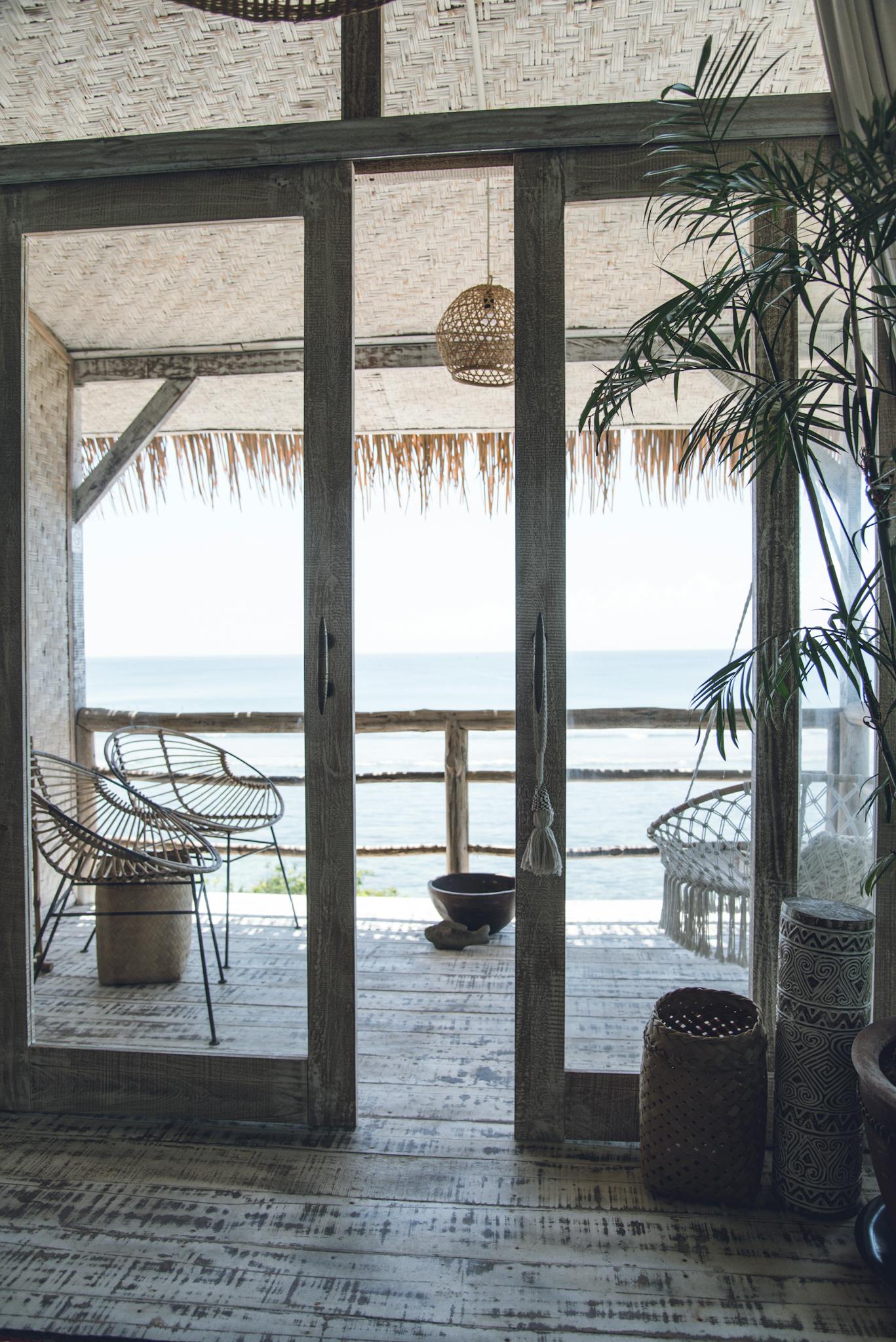 Relaxing seaside retreat with open doors to a rustic wooden balcony overlooking the ocean.